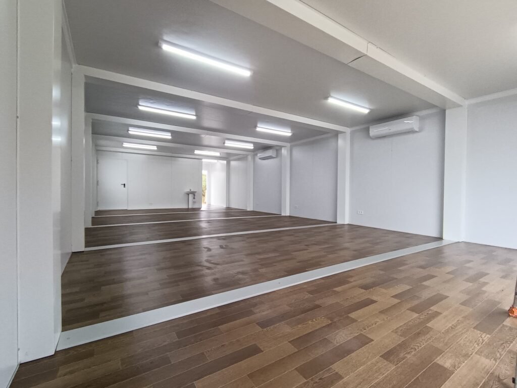 Intérieur d'un atelier modulaire PACA MODUL de 90 m² à Bollène : murs lisses blancs RAL 9003, lino imitation parquet, éclairage LED, 2 climatisations murales, évier