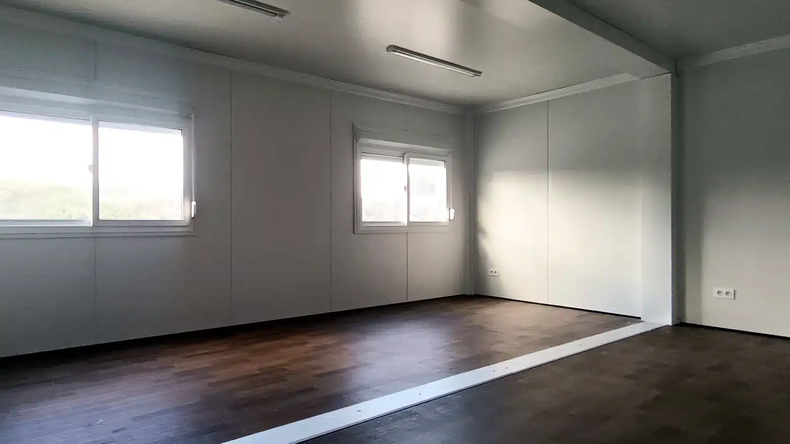 Intérieur de la salle double modulaire livrée à La Seyne-sur-Mer : pièce ouverte, sol aspect parquet, barre de seuil à la jonction des modules